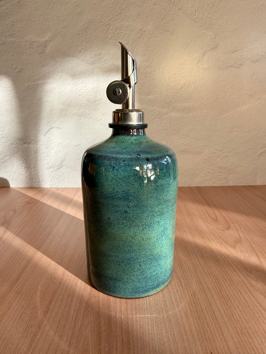 Handmade ceramic olive oil bottle in a glossy turquoise glaze with steel spout