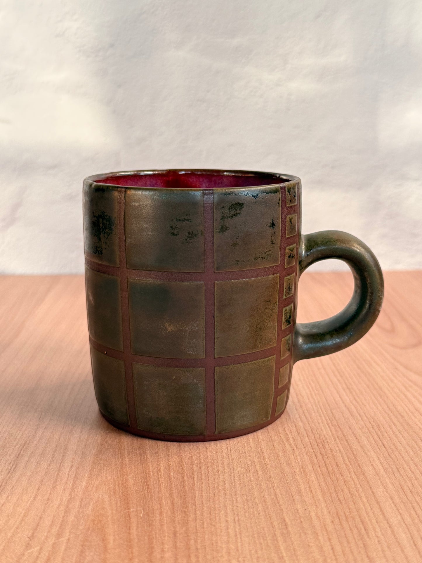 Handmade ceramic mug with carved grid texture and olive bronze glaze