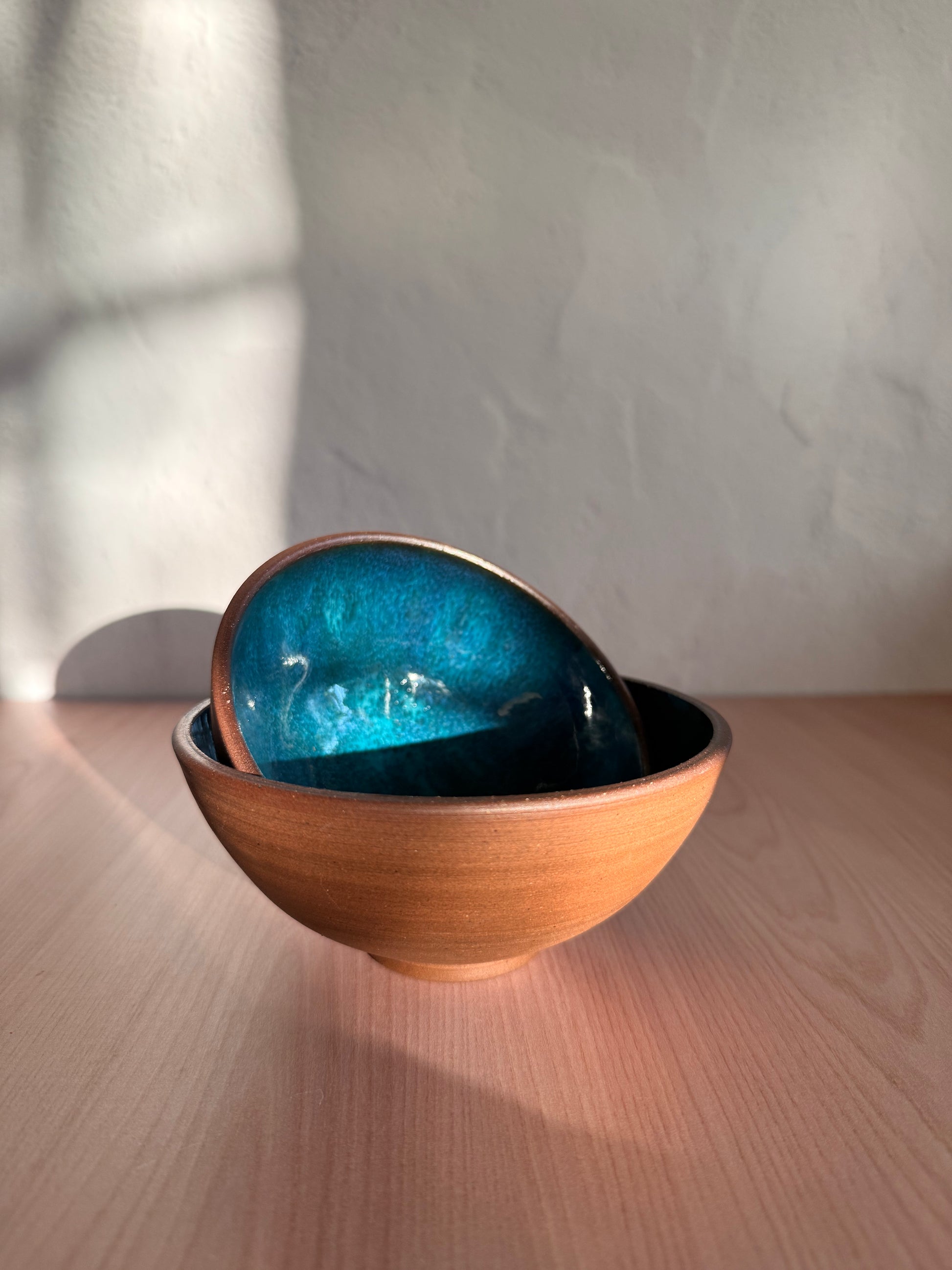 Set of two handmade ceramic bowls with teal interior glaze, nested