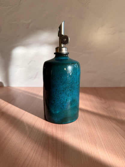 Handmade ceramic olive oil bottle in a deep teal glaze with steel spout